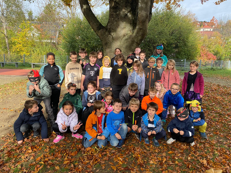 Kindergruppe vor einem Baum im Schulgarten. - FERIA e.V. in Aidlingen